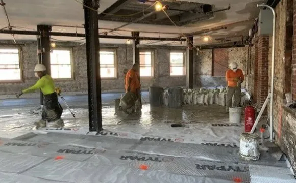 Crew installing subfloor and vapor barrier during a historic building interior renovation